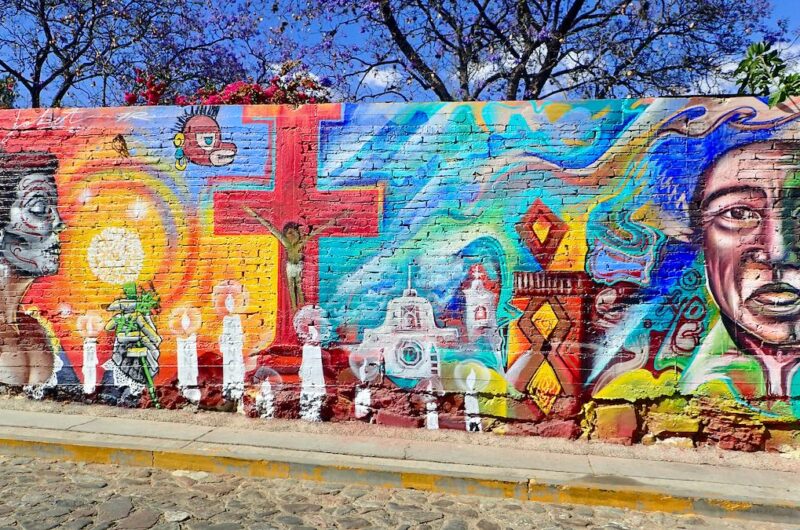 Brightly colored mural with a child on a red cross and a woman with her face painted like a skull.