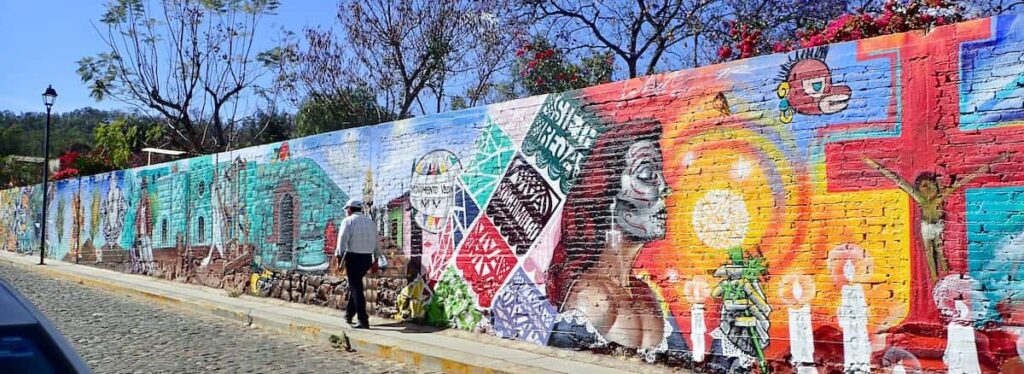 sweeping, colorful mural on a brick wall by a cobbled street