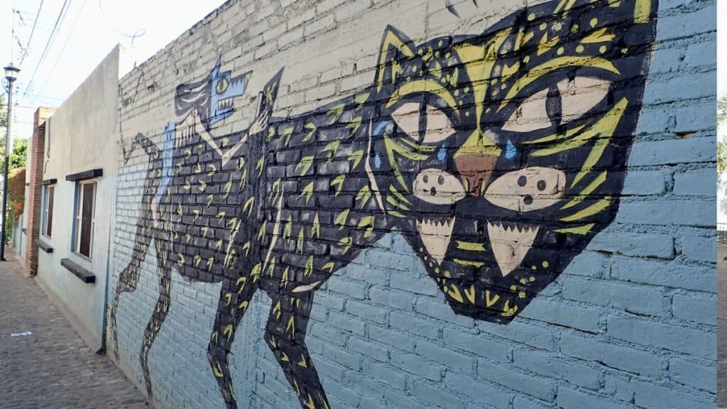 mural of black cat with blue mouse person riding on back