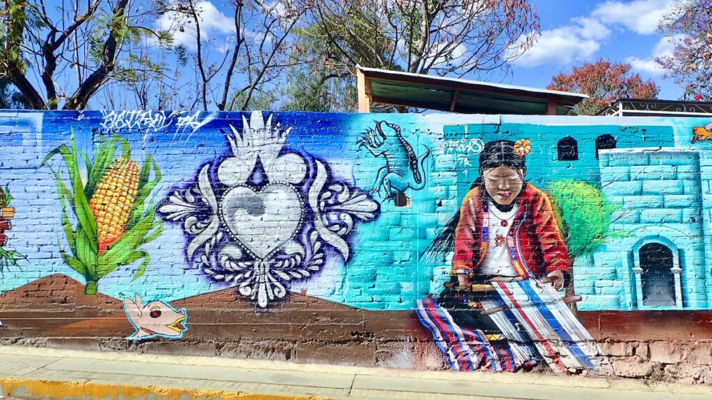 mural of decorated heart, corn, and woman weaving yarn